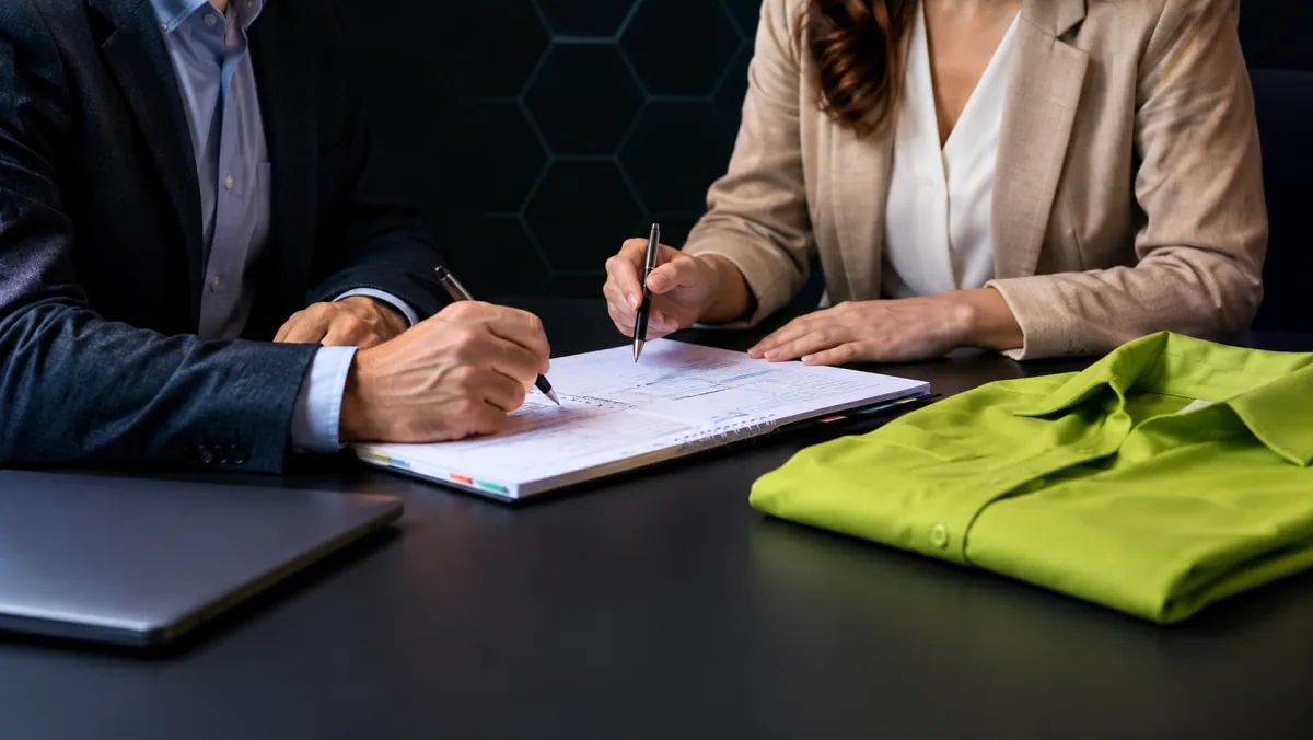 Un consultant et une dirigeante d'entreprise annotent ensemble un cahier des charges de formation sur une table de réunion.